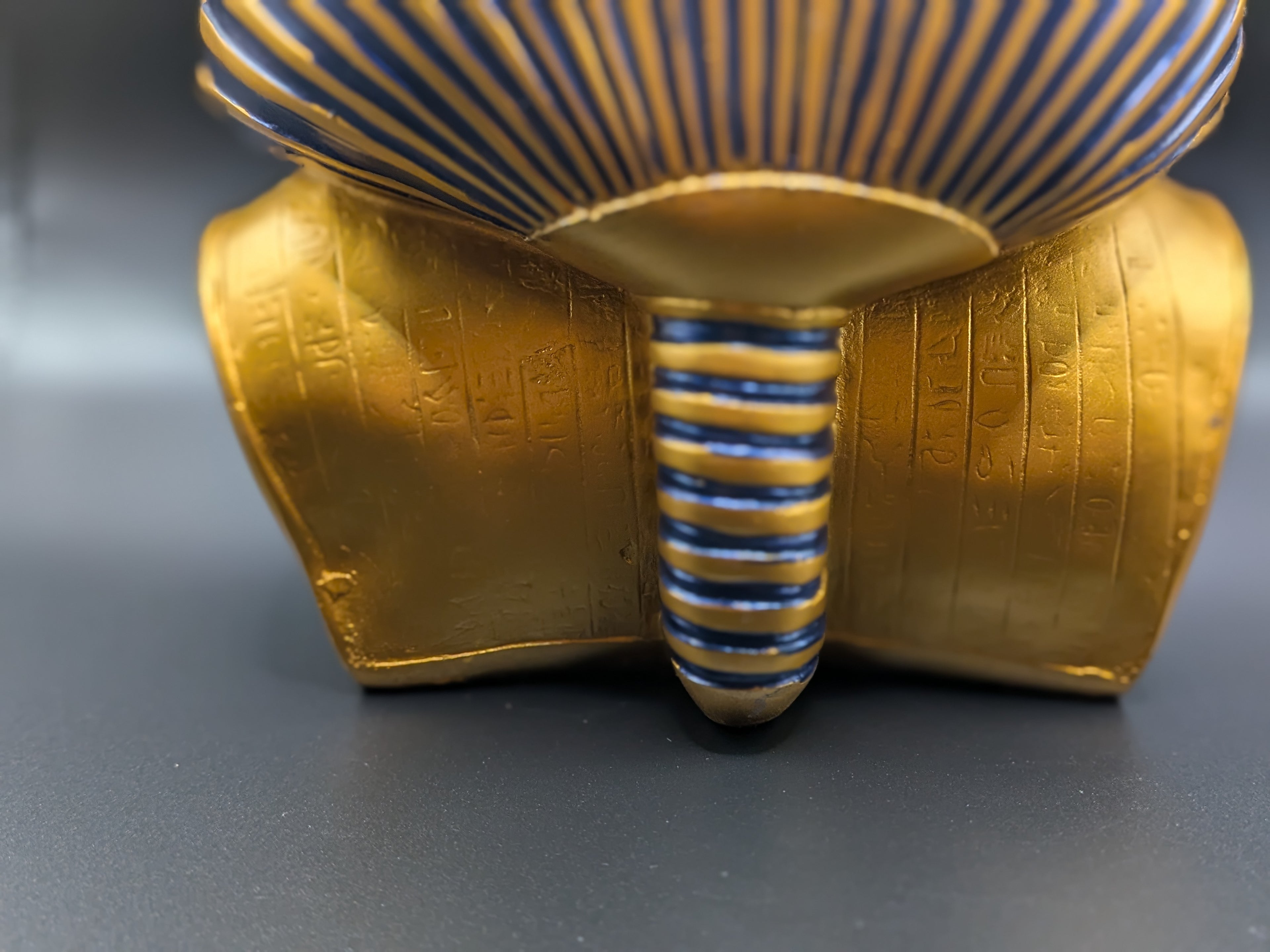 Gold and blue striped decorative item on a gray background