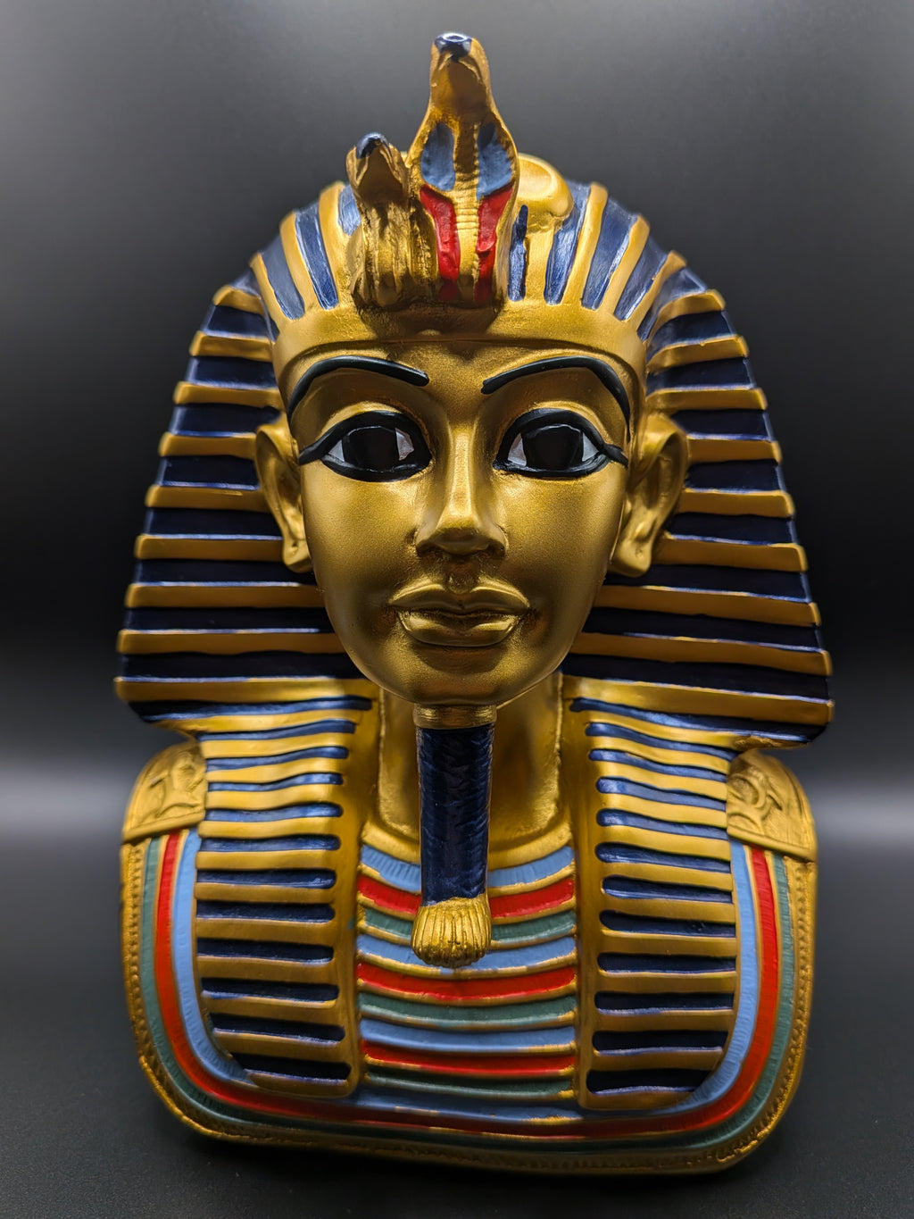 Gold Egyptian pharaoh mask with colorful details on a dark background